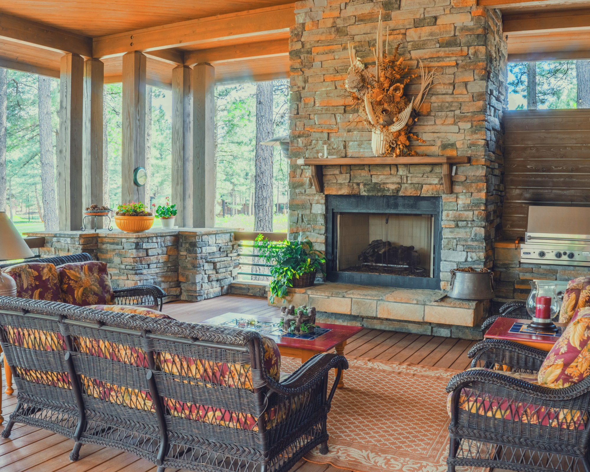Covered porch lounge with a stacked-stone fireplace and wicker seating